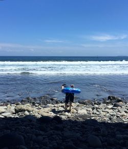 Man standing on beach against blue sky