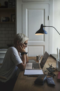 Side view of female designer working late at home office