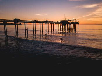 Silhouette pier on beach against sky during sunset