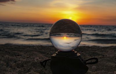 Light candle on beach against sky during sunset