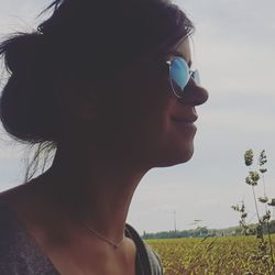 Close-up of young woman wearing sunglasses on field against sky