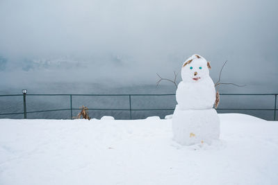 Snowman and white snow on land against sky during winter