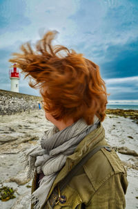 Rear view of woman at beach against sky