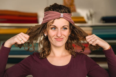 Creative designer sporting a trendy headband while playfully adjusting her curly hair