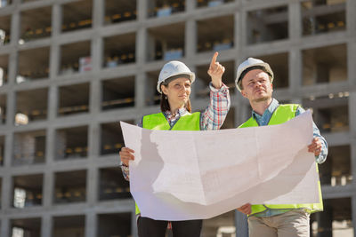 Portrait of smiling young woman standing against building