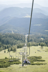 Portrait of women sitting on overhead cable car against mountains
