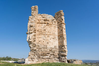 Low angle view of old ruins against clear blue sky