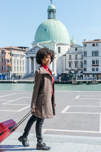 Full length of woman standing against building in city