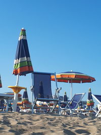 Deck chairs on beach against clear blue sky