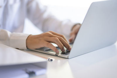 Close-up of woman using laptop on table