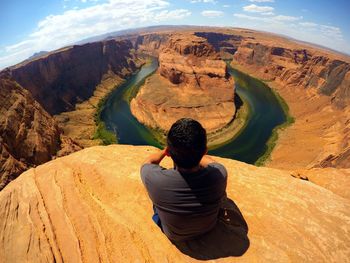 Rear view of man sitting in front of mountains