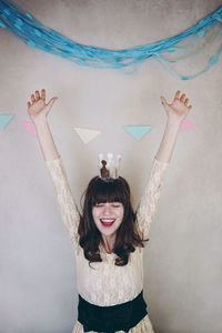 Portrait of smiling young woman standing against wall