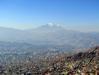 Aerial view of city by mountains against clear sky