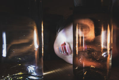 Portrait of woman looking through glass bottle