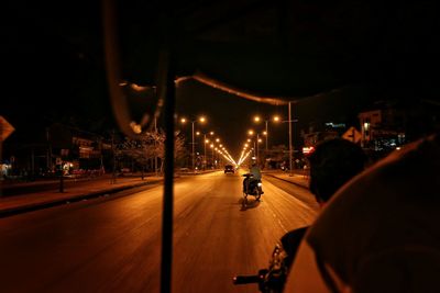 Empty road along lit street lights at night