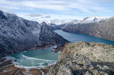 Scenic view of turquoise glacier lake flowing into the gjende lake between snowcapped mountains