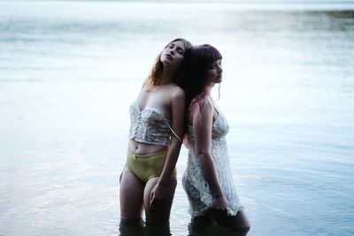 Young woman standing at beach against sky