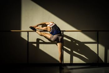 MAN SITTING ON RAILING AGAINST WALL