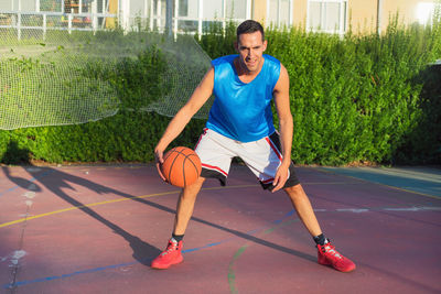 Full length of man dribbling basketball on court