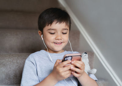 Child wearing earphones listening relaxing music.boy playing game on mobile phone, 