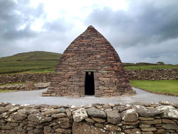 Stone hut on field against sky