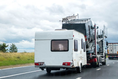 View of vehicles on road against cloudy sky