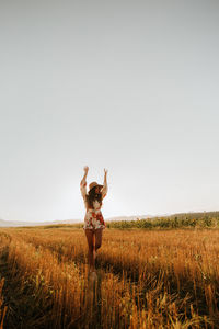 Woman standing on field against clear sky