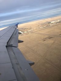 Airplane flying over airport runway against sky