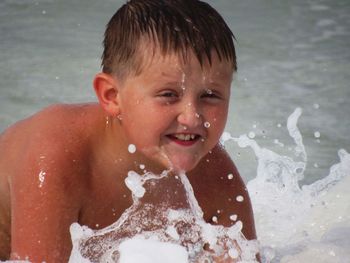 Close-up of shirtless boy swimming in sea
