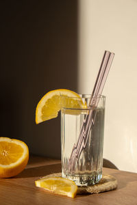 Glass of water with fresh lemon juice with reusable glass straws detox cold tonic water with sunny