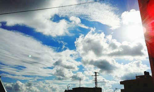 Low angle view of electricity pylon against cloudy sky