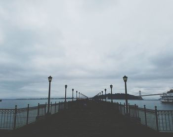 Pier on sea against cloudy sky