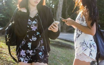 Midsection of women using mobiles at park