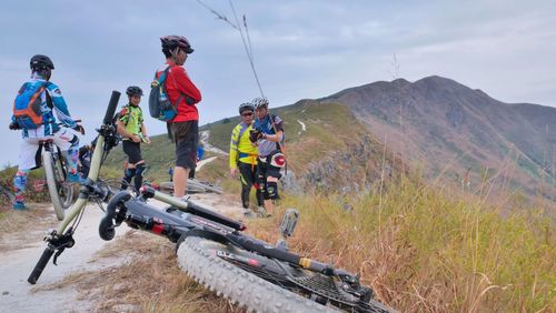 Men with bicycle on mountain against sky