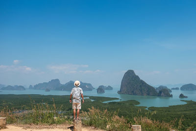 Rear view of man standing on land against sky