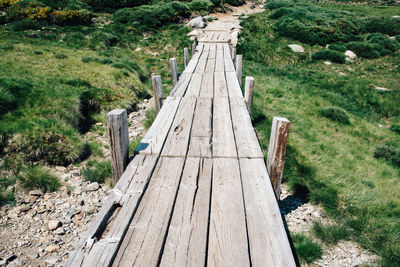 Boardwalk amidst grassy field on hill