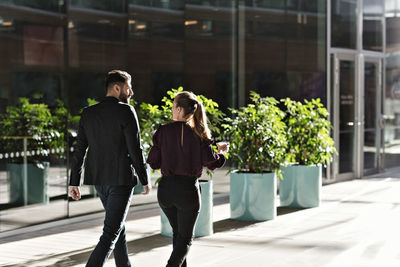 Business colleagues talking while walking in lobby at office