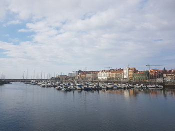 Sailboats in city by river against sky