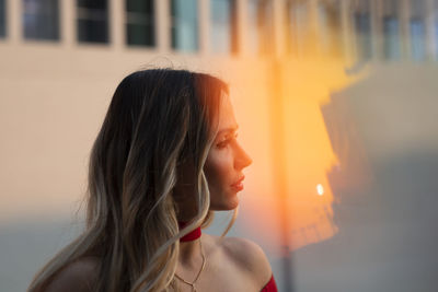 Close-up portrait of young woman looking away at sunset