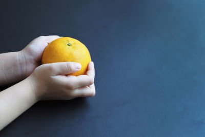 Close-up of hand holding apple against orange background