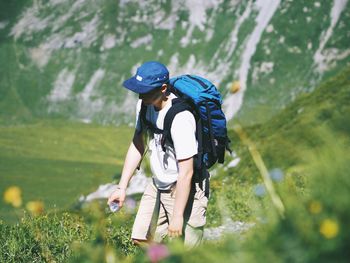 Hiker with backpack on field against mountain
