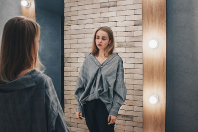 Young woman standing against illuminated wall