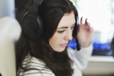 Close-up of young woman listening music through headphones at home