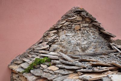 Ruined stone house against pink wall