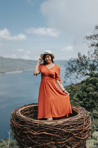 Portrait of smiling young woman standing against sky