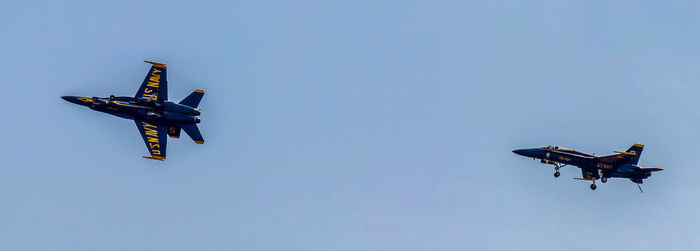 Low angle view of airplane flying against clear blue sky