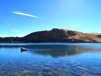 Scenic view of glacial blue lake against blue sky