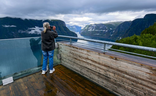 Rear view of man standing on railing against mountain