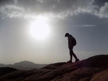 Side view of backpack man standing on cliff