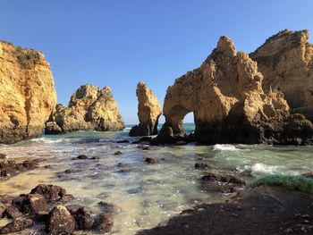 Rocks on beach against clear blue sky